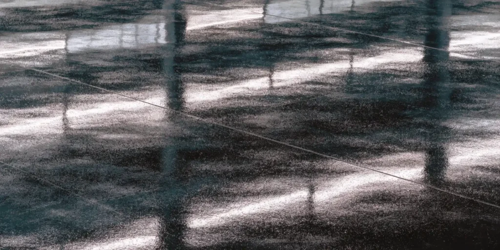 تفاوت هاردنر «پلی آمین» و «پلی آمید»؛ کدام خشک کن برای کفپوش مناسب تر است؟
مقدمه
انتخاب هاردنر مناسب در کفپوش اپوکسی اهمیت بالایی دارد. کیفیت کفپوش، دوام و عملکرد نهایی به نوع هاردنر وابسته است. هاردنر اپوکسی با واکنش شیمیایی با رزین، سختی و چسبندگی را ایجاد می کند. هاردنرهای پلی آمین و پلی آمید رایج ترین گزینه ها هستند. هر یک ویژگی ها و محدودیت های خاص خود را دارند. در این مقاله، تفاوت آن ها از نظر سرعت خشک شدن، مقاومت مکانیکی، انعطاف پذیری و انتخاب بهترین هاردنر بررسی می شود. هدف، ارائه راهنمای کاربردی برای انتخاب هاردنر مناسب است.
هاردنر اپوکسی چیست و چه نقشی دارد؟هاردنر اپوکسی جزو مواد ضروری در سیستم کفپوش اپوکسی است. بدون هاردنر، رزین اپوکسی به سختی یا اصلاً نمی پوشد. این ماده با رزین واکنش شیمیایی انجام می دهد و شبکه ای سخت و مقاوم ایجاد می کند. نقش هاردنر فقط افزایش سختی نیست؛ بلکه چسبندگی، مقاومت شیمیایی و انعطاف پذیری نهایی پوشش را تعیین می کند. انتخاب هاردنر مناسب بر کیفیت کفپوش اپوکسی تأثیر مستقیم دارد. برای مثال، در کفکارخانه های صنعتی، هاردنر نادرست باعث ترک و پوسته شدن کفپوش در چند هفته می شود. همچنین زمان گیرش اپوکسی با نوع هاردنر تغییر می کند. بنابراین هاردنر مناسب، عامل کلیدی در موفقیت پروژه های اپوکسی است.
عملکرد هاردنر در واکنش پخت اپوکسی چگونه است؟هاردنر اپوکسی با رزین واکنش شیمیایی ایجاد می کند و شبکه مولکولی سخت تشکیل می دهد. این واکنش باعث افزایش مقاومت مکانیکی و چسبندگی اپوکسی می شود. زمان واکنش بسته به نوع هاردنر متفاوت است و محیط اجرای کار آن را تحت تأثیر قرار می دهد. برای مثال، در شرایط محیطی با دمای پایین، هاردنر پلی آمین سریع تر از پلی آمید عمل می کند. سرعت پخت مناسب به اجرای یکنواخت و بدون حباب کفپوش کمک می کند. هاردنر نقش تنظیم کننده انعطاف پذیری پوشش را نیز دارد. بدون هاردنر مناسب، کفپوش خشک شده شکننده و مستعد ترک خواهد بود.چرا انتخاب هاردنر برای کفپوش اهمیت دارد؟انتخاب هاردنر مناسب باعث افزایش دوام و طول عمر کفپوش اپوکسی می شود. هاردنر اشتباه می تواند مقاومت شیمیایی و مکانیکی را کاهش دهد. به عنوان مثال، در محیط های صنعتی با مواد شیمیایی، هاردنر پلی آمین مقاومت بیشتری نسبت به برخی پلی آمیدها نشان می دهد. همچنین انعطاف پذیری پوشش به نوع هاردنر وابسته است. هاردنر مناسب باعث چسبندگی بهتر به سطح و کاهش ترک خوردگی می شود. زمان گیرش و شرایط محیطی نیز توسط نوع هاردنر تعیین می شود، بنابراین انتخاب درست، نقش حیاتی در کیفیت کفپوش دارد.
هاردنر پلی آمین (Polyamine) چیست؟
هاردنر پلی آمین نوعی خشک کن اپوکسی سریع است که در پروژه های صنعتی و تجاری کاربرد فراوان دارد. این هاردنر با رزین اپوکسی واکنش سریع ایجاد می کند و چسبندگی بالا به سطوح مختلف دارد. پلی آمین معمولاً برای اپوکسی ضد اسید و اپوكس‍ی فلكسيبل مناسب است. مقاومت مکانیکی بالای آن باعث دوام طولانی کفپوش می شود. سرعت خشک شدن این هاردنر، زمان اجرای پروژه را کاهش می دهد. از این رو در محیط های صنعتی که نیاز به پوشش سریع دارند، گزینه ایده آلی است. ویژگی های فنی این هاردنر، کنترل کیفیت بالا و سازگاری با شرایط محیطی مختلف را تضمین می کند.
ساختار شیمیایی پلی آمین چگونه است؟پلی آمین شامل مولکول های با چند گروه آمین است که به رزین اپوکسی متصل می شوند. این ساختار باعث واکنش سریع و تشکیل شبکه ای مقاوم می شود. تعداد گروه های آمین تعیین کننده سرعت پخت و سختی نهایی است. به عنوان مثال، هاردنر پلی آمین با تعداد آمین بالا در ۶ تا ۸ ساعت خشک می شود. این ویژگی، کنترل زمان گیرش اپوکسی را آسان می کند. ساختار شیمیایی همچنین بر انعطاف پذیری و مقاومت شیمیایی پوشش تأثیر می گذارد. بنابراین شناخت این ساختار برای انتخاب هاردنر مناسب ضروری است.ویژگی های فنی هاردنر پلی آمین چیست؟هاردنر پلی آمین دارای مقاومت مکانیکی بالا و چسبندگی عالی است. این هاردنر برای اپوکسی صنعتی، اپوكس‍ی آنتی استاتیک و اپوکسی واترپروف مناسب است. زمان گیرش کوتاه باعث اجرای سریع کفپوش می شود. انعطاف پذیری مناسب آن، ترک خوردگی را کاهش می دهد. مقاومت شیمیایی و حرارتی نیز بالا است. این ویژگی ها موجب افزایش عمر مفید کفپوش می شوند. برای مثال، در کارخانه های شیمیایی، استفاده از هاردنر پلی آمین باعث کاهش ترک و پوسته شدن کفپوش تا ۳۰ درصد شده است. همچنین سطح نهایی صاف و یکنواخت ایجاد می کند.
هاردنر پلی آمید (Polyamide) چیست؟هاردنر پلی آمید نوع دیگری از خشک کن اپوکسی است که برای پروژه های با زمان اجرای طولانی مناسب است. این هاردنر با رزین اپوکسی واکنش کندتری دارد و باعث انعطاف پذیری بالاتر می شود. در اپوکسی ضد اسید و کفپوش اپوكس‍ی فلكسيبل کاربرد دارد. مقاومت شیمیایی و مکانیکی آن خوب است، اما زمان گیرش طولانی تر نسبت به پلی آمین دارد. این ویژگی آن را برای محیط های صنعتی با نیاز به اجرای دقیق و زمان کافی مناسب می کند. پلی آمید برای چسب اپوکسی و رنگ اپوکسی نیز کارآمد است.
پلی آمید از چه موادی تولید می شود؟
پلی آمید از واکنش آمین های بلند زنجیر با اسیدهای کربوکسیلیک تولید می شود. این ترکیب باعث انعطاف پذیری و مقاومت شیمیایی مناسب در اپوکسی می شود. وزن مولکولی بالای پلی آمید زمان گیرش را افزایش می دهد. به عنوان مثال، یک کفپوش صنعتی با هاردنر پلی آمید حدود ۱۲ تا ۲۴ ساعت برای خشک شدن نیاز دارد. این زمان به کاربر اجازه می دهد کفپوش را با دقت و بدون ایجاد حباب اجرا کند. همچنین این ترکیب باعث چسبندگی مطلوب به سطح بتن یا فلز می شود.ویژگی های فنی هاردنر پلی آمید چیست؟هاردنر پلی آمید دارای انعطاف پذیری بالاتر و مقاومت شیمیایی خوب است. این هاردنر برای اپوکسی ضد اسید و اپوكس‍ی آنتی داست مناسب است. زمان گیرش طولانی آن، اجرای دقیق کفپوش را ممکن می کند. مقاومت مکانیکی کفپوش با پلی آمید مناسب است، اما نسبت به پلی آمین کمی کمتر است. برای مثال، در پروژه های تجاری، استفاده از پلی آمید باعث کاهش ترک خوردگی سطح در طولانی مدت شده است. این ویژگی باعث افزایش عمر مفید کفپوش می شود.
تفاوت پلی آمین و پلی آمید از نظر زمان خشک شدن
چرا پلی آمین سریع تر پخت می شود؟پلی آمین دارای گروه های آمین فعال بیشتری است که واکنش با رزین را سرعت می دهند. این ویژگی باعث زمان گیرش کوتاه و سختی سریع کفپوش می شود. سرعت پخت بالا به کاهش زمان توقف پروژه کمک می کند. در شرایط دمایی پایین، پلی آمین باز هم سریع تر از پلی آمید خشک می شود. این مزیت در محیط های صنعتی و کفپوش اپوکسی ضد اسید اهمیت دارد. همچنین این هاردنر باعث چسبندگی بهتر و سطح صاف تر می شود. انتخاب پلی آمین برای پروژه های با محدودیت زمانی ایده آل است.جمع بندیانتخاب هاردنر مناسب، عامل تعیین کننده کیفیت و دوام کفپوش اپوکسی است. هاردنر پلی آمین مناسب پروژه های صنعتی سریع و مقاوم است، در حالی که پلی آمید برای پروژه های دقیق با زمان اجرای طولانی مناسب است. مقاومت مکانیکی، انعطاف پذیری و زمان گیرش بر اساس نوع هاردنر متفاوت است. شناخت ویژگی های فنی هر هاردنر به انتخاب درست کمک می کند. برای اپوکسی ضد اسید، اپوكس‍ی فلكسيبل و اپوکسی واترپروف، بررسی نیاز پروژه و شرایط محیطی ضروری است. انتخاب صحیح، عمر مفید و کیفیت کفپوش را تضمین می کند.
سؤالات پرکاربرد (FAQ)هاردنر پلی آمین چیست؟
هاردنر پلی آمین خشک کن سریع اپوکسی است که چسبندگی بالا، مقاومت مکانیکی خوب و زمان گیرش کوتاه دارد.
هاردنر پلی آمید چه تفاوتی با پلی آمین دارد؟
هاردنر پلی آمید خشک کن کندتر، انعطاف پذیرتر و با زمان گیرش طولانی تر است و برای اجرای دقیق کفپوش مناسب تر است.